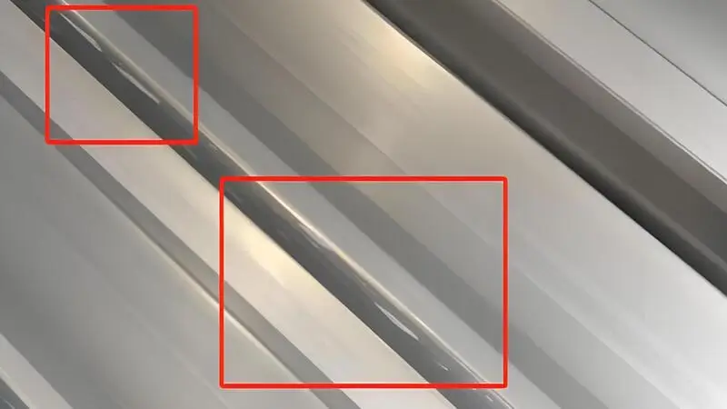 Nahaufnahme einer Kunststoff-Extrusionsanlage, die ein durchgehendes Profil herstellt, mit sichtbaren Kratzern auf der Oberfläche des extrudierten Materials.