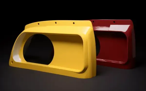 A yellow and a red automotive part with a circular cutout, placed against a dark background.
