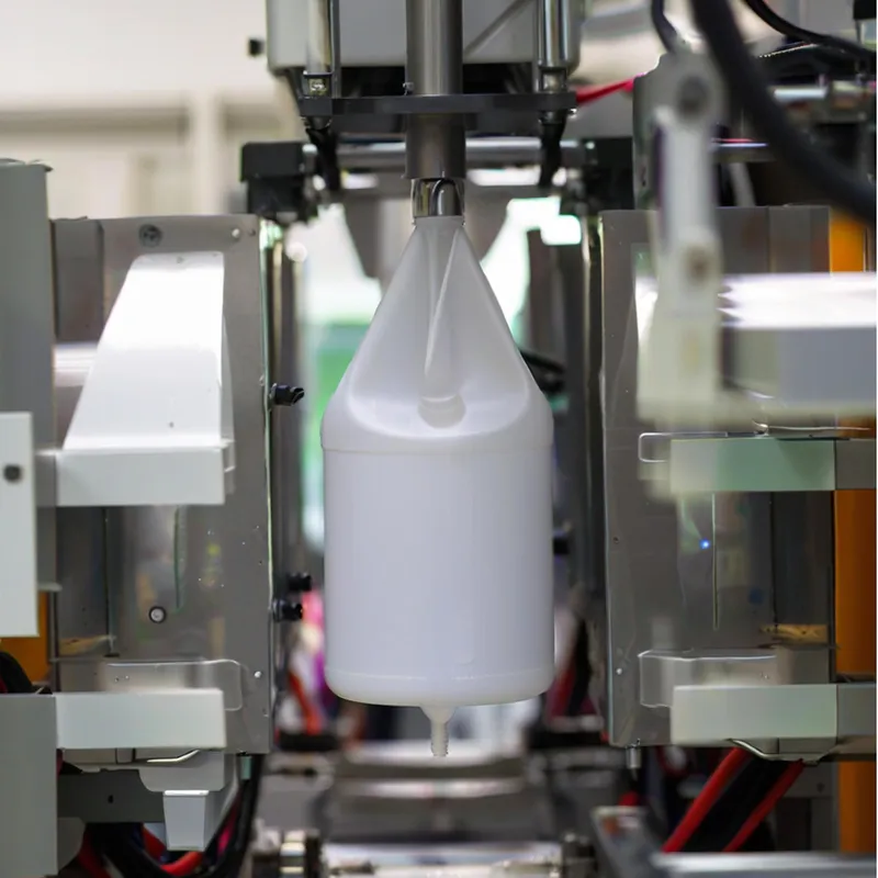 A plastic bottle being formed inside an industrial molding machine.