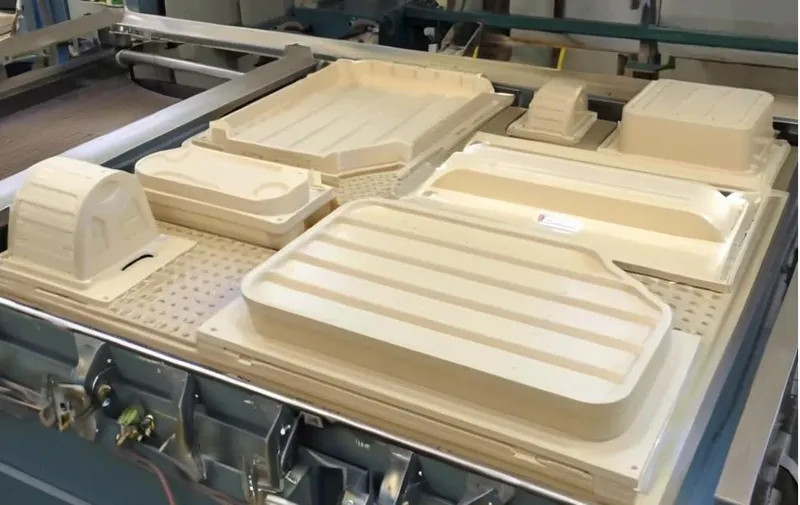 A CNC machine with various rectangular and arched wooden parts arranged on the worktable.