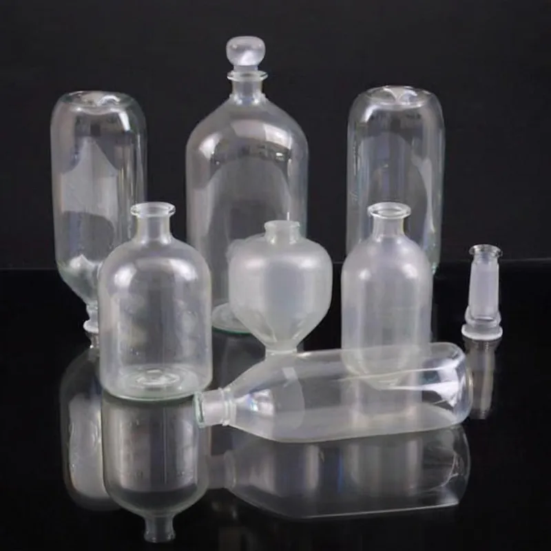 A group of seven different glass bottles arranged on a reflective black surface.