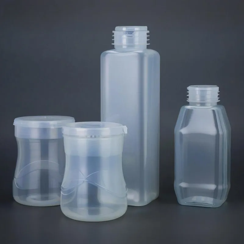 A set of clear plastic bottles and jars with different shapes and sizes on a dark background.