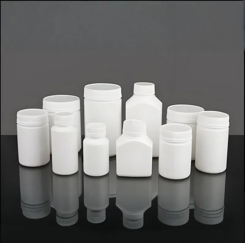 A collection of white plastic bottles and jars in various shapes and sizes on a reflective surface.