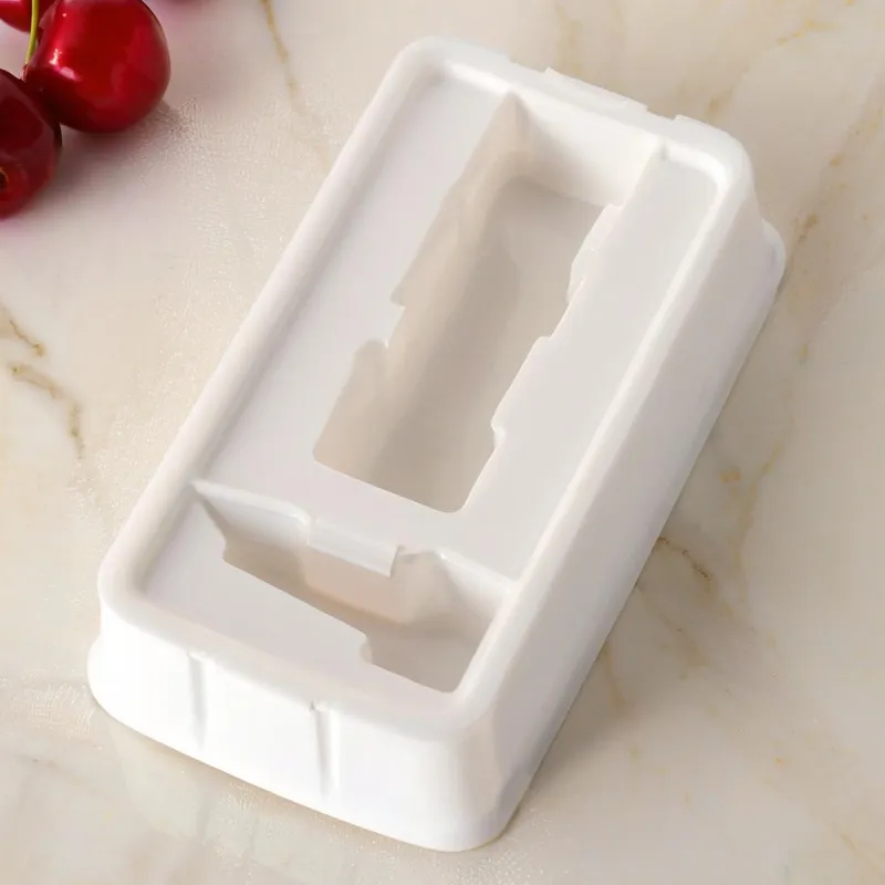 White rectangle plastic mold on a marble surface next to cherries.