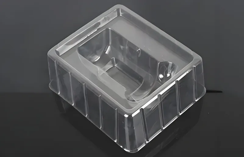 A clear plastic packaging tray on a dark surfac