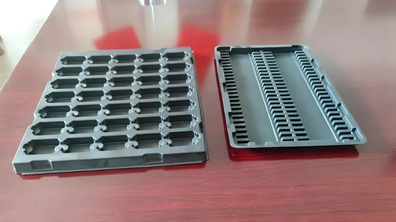 Two black plastic stacking trays on a wooden surface
