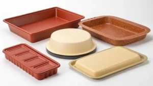 A variety of baking trays and molds in different shapes and colors including red, beige, and brown.
