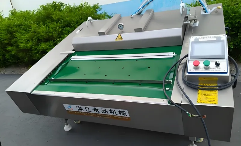 A large automated food processing machine with a digital control panel, featuring a stainless steel body and green conveyor belt