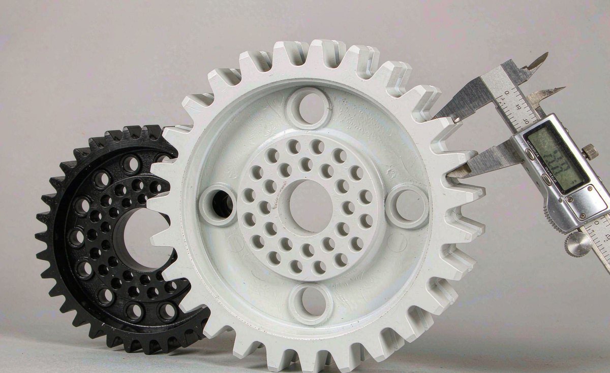 White POM and black PA66 precision gears being measured with a digital caliper