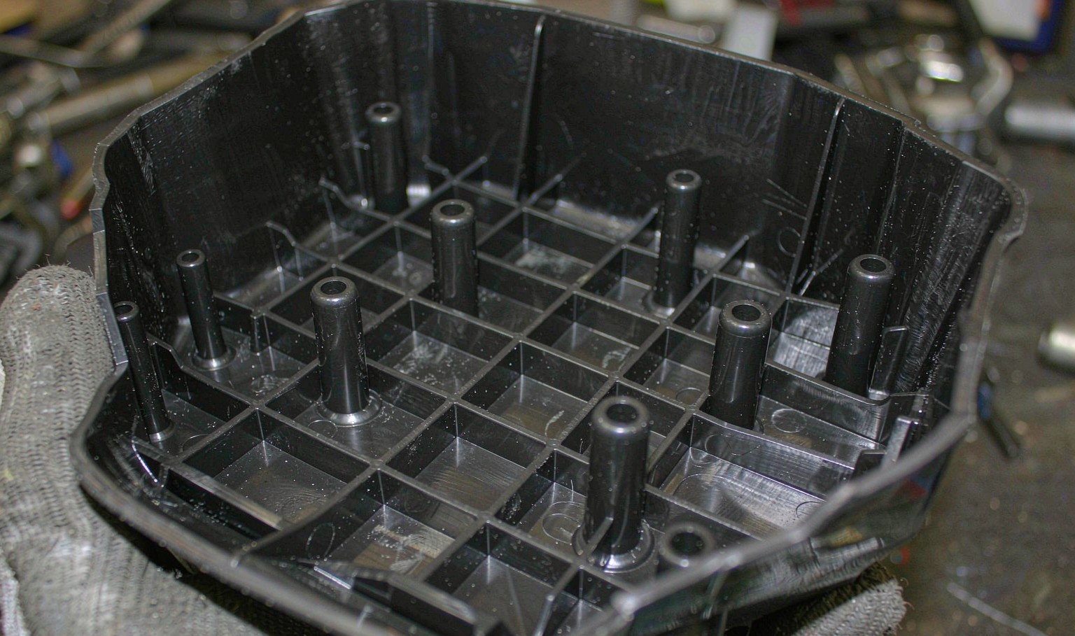 Inside of a moulded black ABS enclosure showing a grid of reinforcing ribs and cylindrical screw bosses