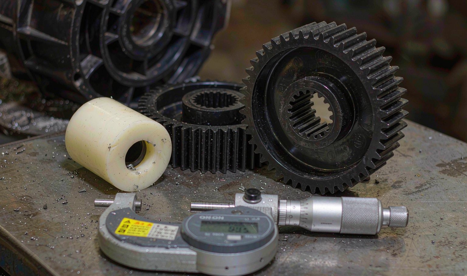 Black glass filled nylon gears and a natural nylon bush on a metrology bench with a micrometer