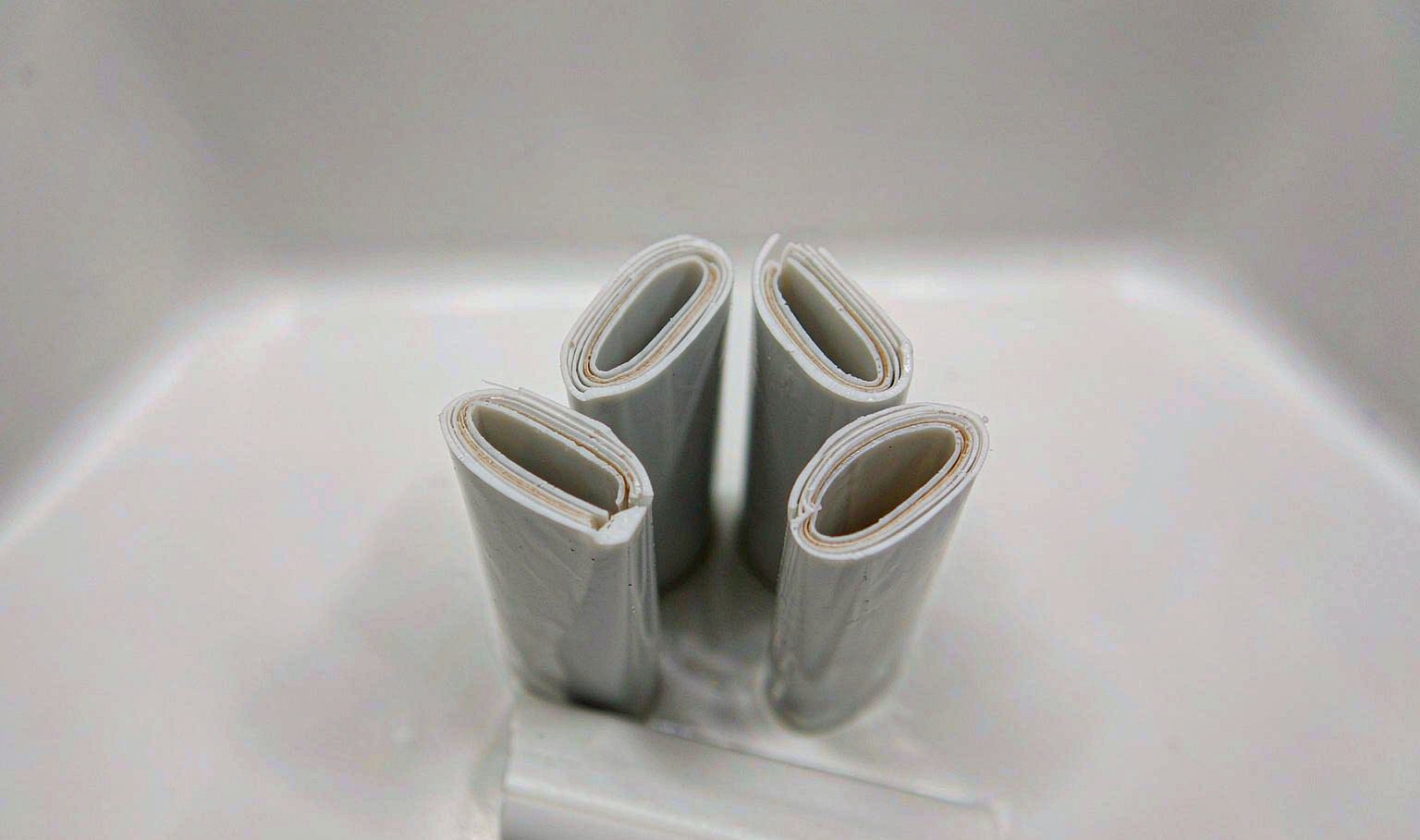 Cut sections of a co-extruded plastic tube showing fine concentric barrier layers in the wall