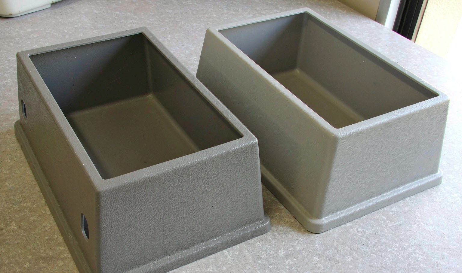 Pressure formed plastic enclosure with sharp moulded-in details and textured surface next to a vacuum formed part of the same shape