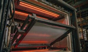 Plastic sheet clamped in a frame inside a thermoforming oven between upper and lower infrared heater banks