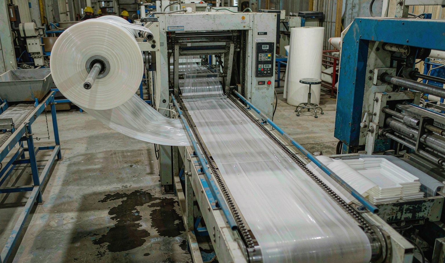 Roll fed thin gauge thermoforming line with a sheet roll, chain rails, oven tunnel and trim station